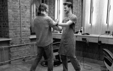 Barber and client greeting each other warmly inside a barbershop