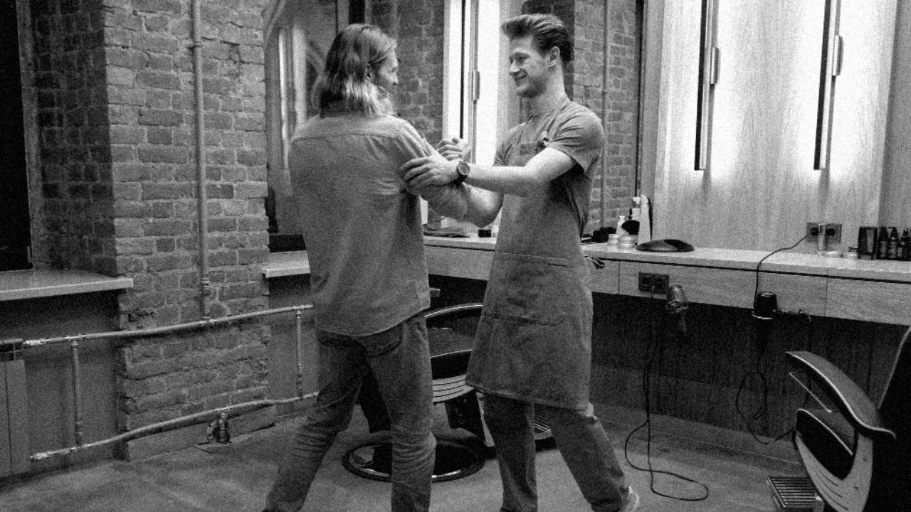 Barber and client greeting each other warmly inside a barbershop