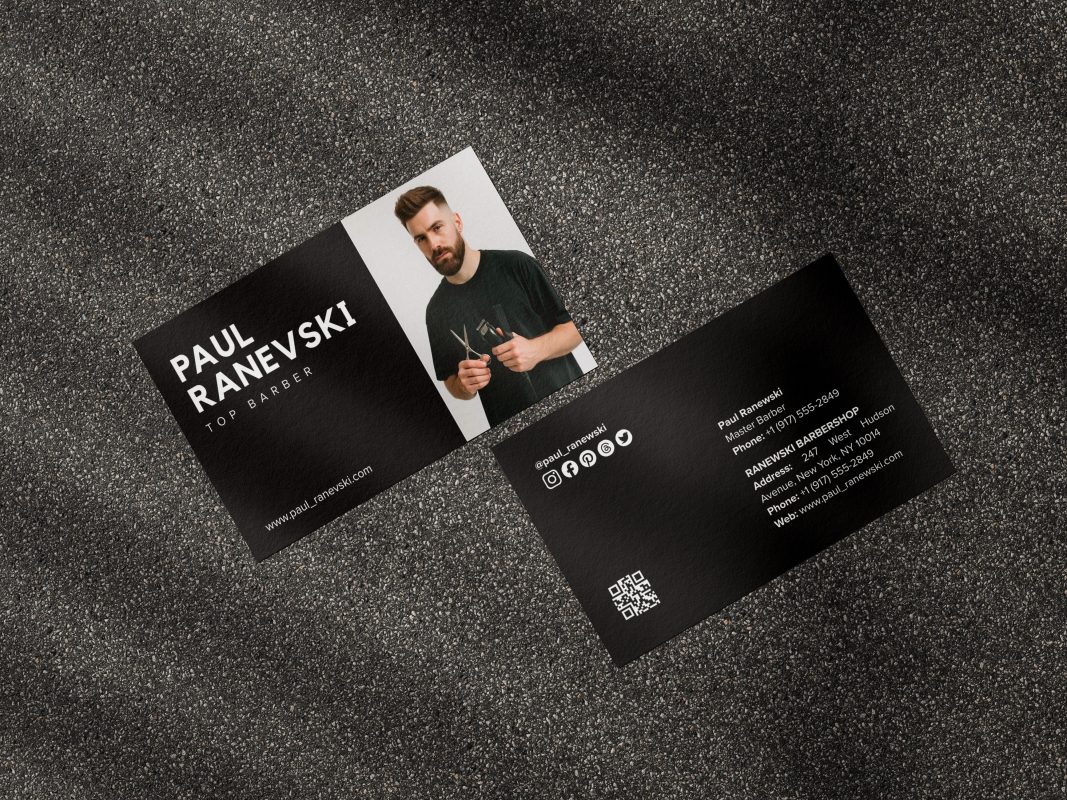 Two-sided black barber business card mockup showing photo and name front with social icons QR code and shop contact reverse