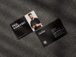 Two-sided black barber business card mockup showing photo and name front with social icons QR code and shop contact reverse