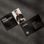 Two-sided black barber business card mockup showing photo and name front with social icons QR code and shop contact reverse