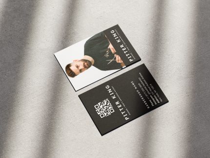 Double-sided solo barber name card template mockup showing full-face photo front and oversized QR booking code on minimal black reverse