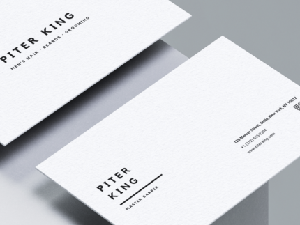 Close-up of minimalist white barber business card template showing black typography, QR code placeholder and contact details