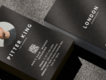 Close-up of double-sided minimal black barber business card template showing barber photo, name and second QR code on the reverse
