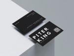 Printed black barber name card held in hand with a phone scanning the QR code on the front, showing real-world booking flow