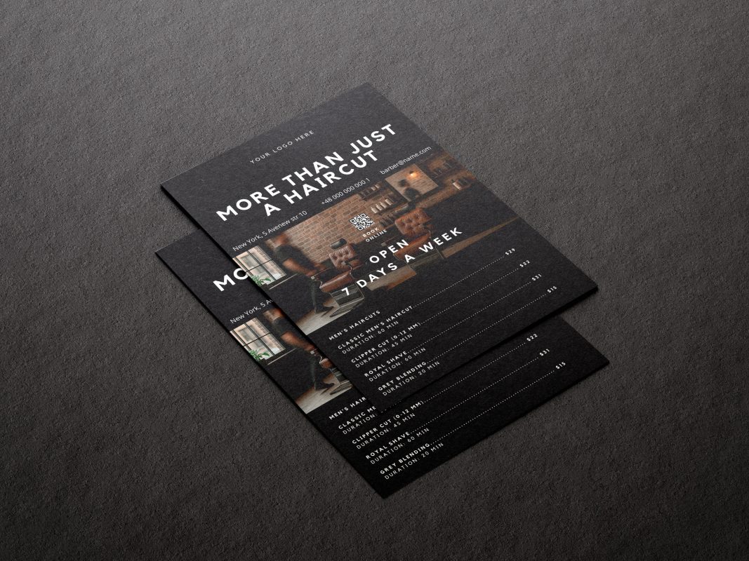 Printed A5 barbershop brochure template in minimal black design displayed on a dark marble surface