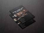 Printed A5 barbershop brochure template in minimal black design displayed on a dark marble surface