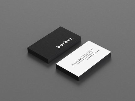 Black and white personal barber business card template showing bold BARBER text on front and contact details on back, flat lay mockup