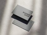 Side-by-side comparison of a busy multi-element barbershop card against the ultra-minimal single-word front grey loft barbershop card template